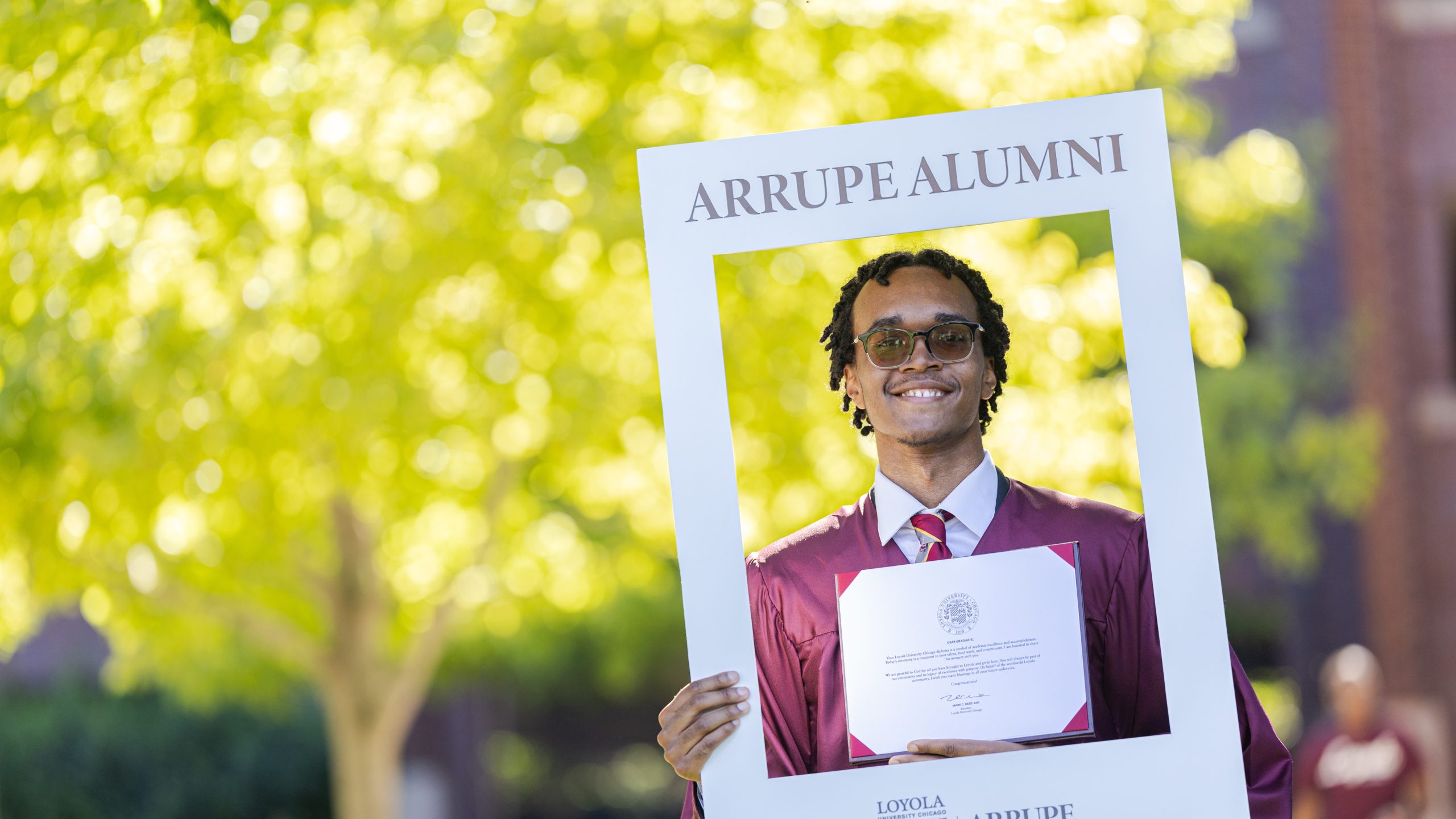 John Cooke poses for a photo with his degree from Arrupe College of Loyola University Chicago.