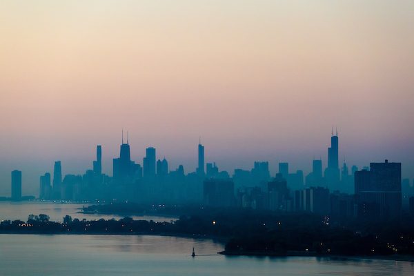 An aerial photo of the city of Chicago at sunset shows the haze clouding the view of the buildings
