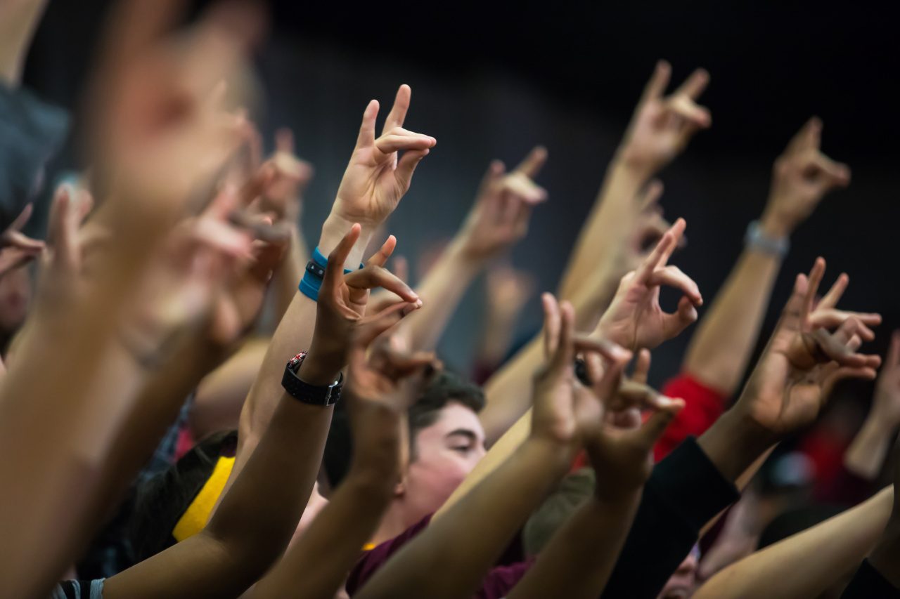 Basketball fans hands in the air making the Rambler hand sign.