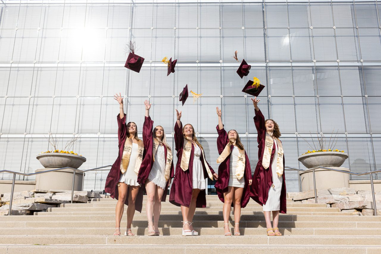 Loyola University Chicago graduates tossing graduation caps in the air in front of IC