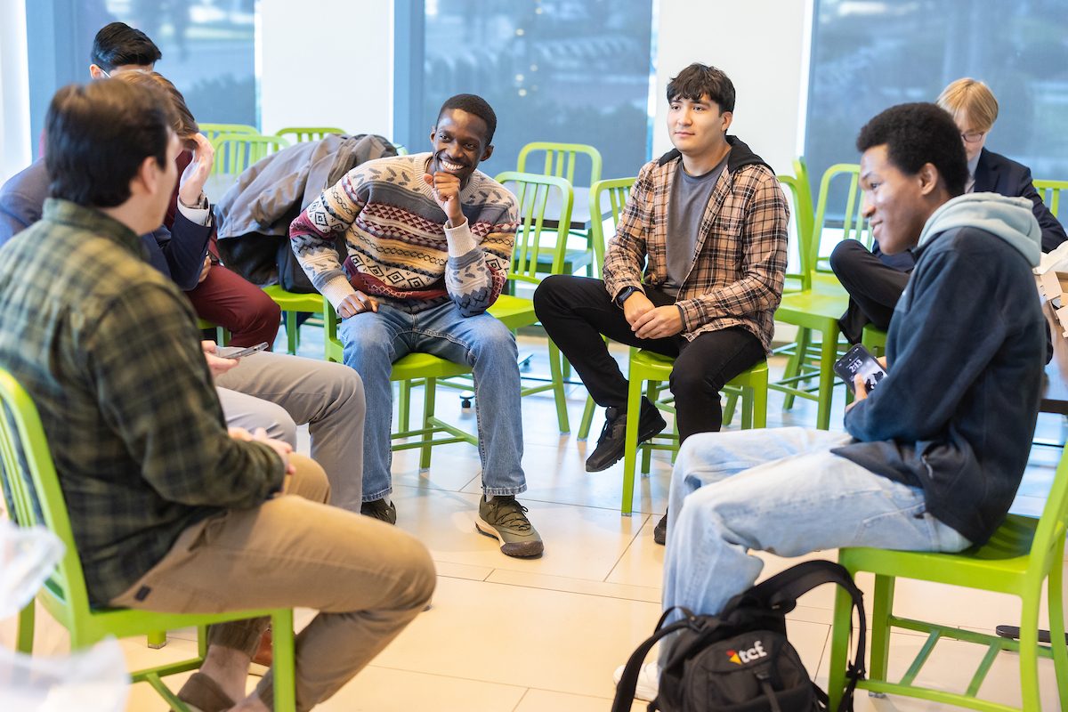 A group of Loyola University Chicago students sit in a circle of lime green chairs