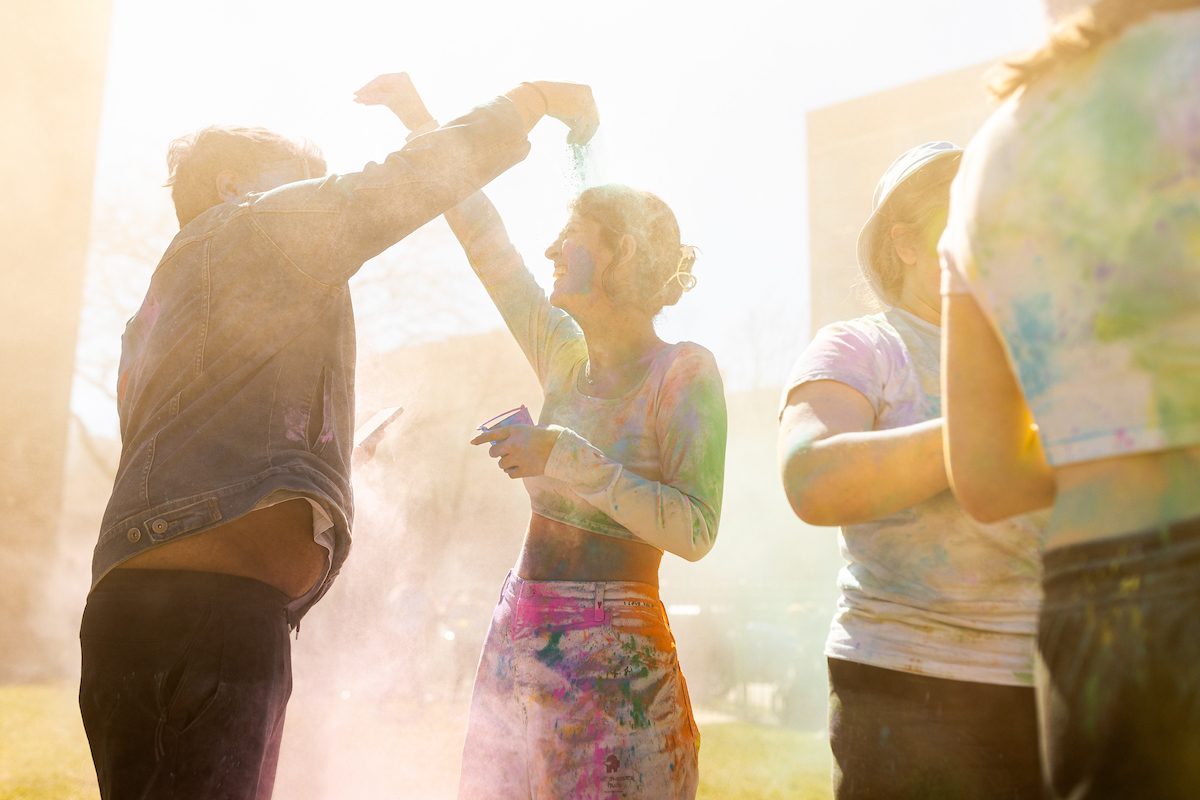 The Hindu Student Association hosts the annual Holi celebration in the Winthrop Play Lot, celebrating the arrival of spring, on April 6, 2024. (Photo by: Lukas Keapproth) Two Loyola University Chicago students covered in multicolored powders sprinkle powder on each other's heads