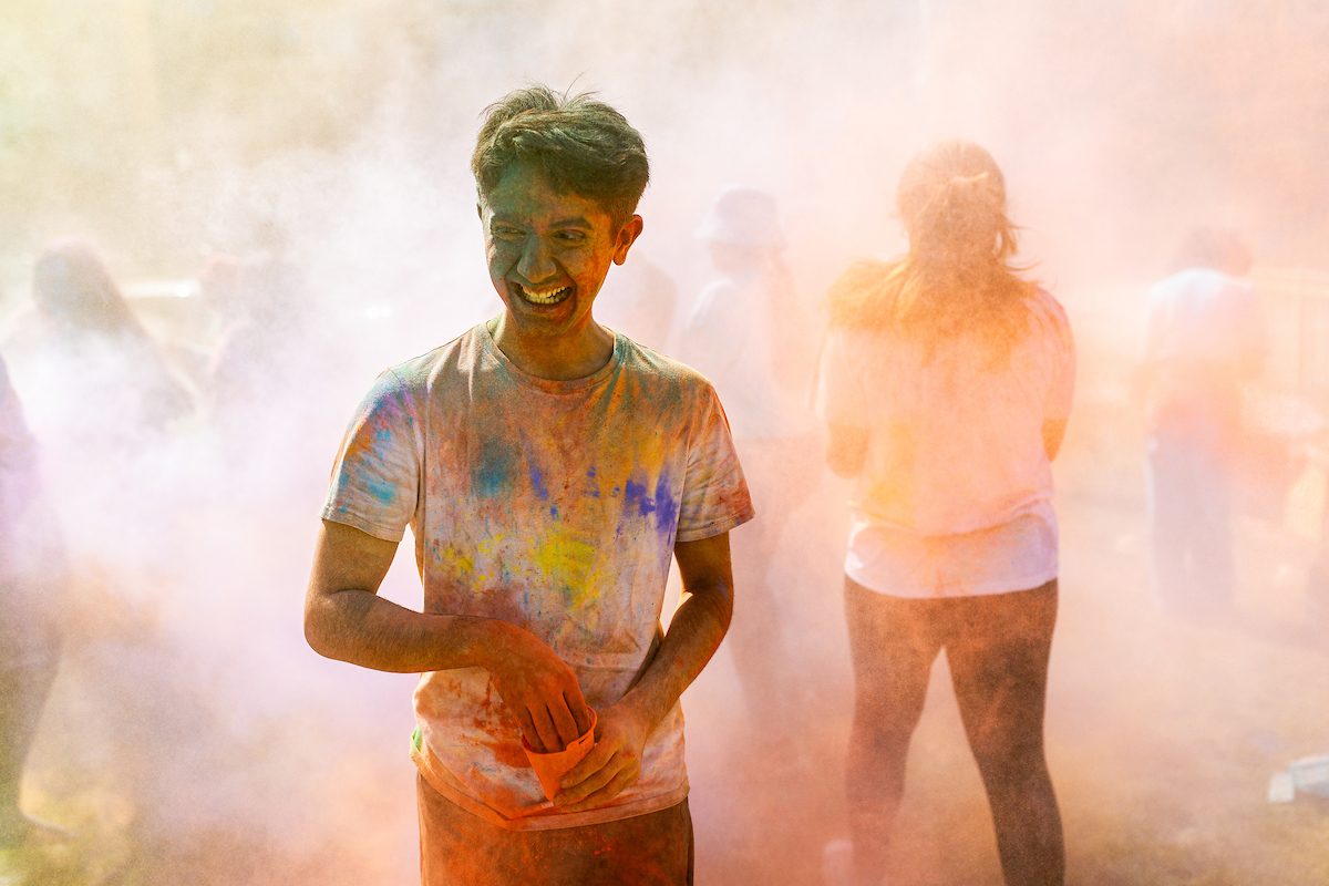 The Hindu Student Association hosts the annual Holi celebration in the Winthrop Play Lot, celebrating the arrival of spring, on April 6, 2024. (Photo by: Lukas Keapproth) A Loyola University Chicago student covered from head to foot in multicolored powders laughs as he reaches into a small container