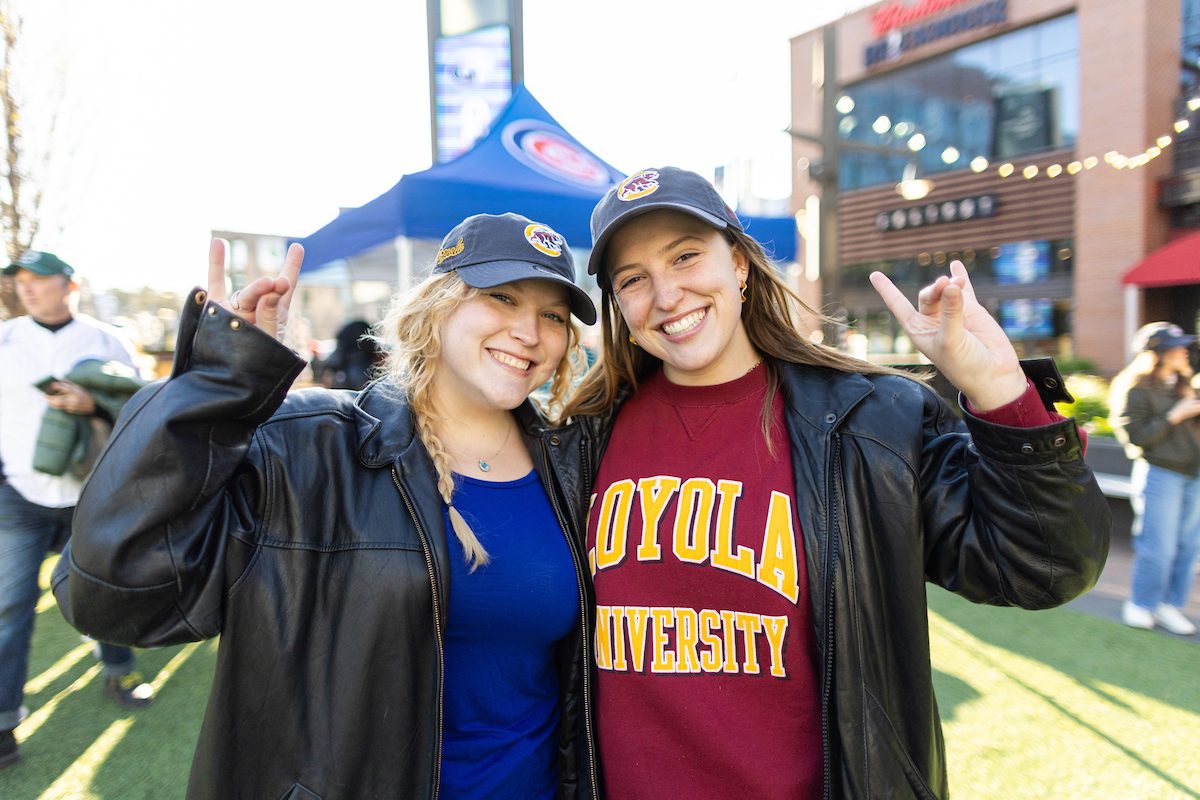 The Chicago Cubs host Loyola Night against the Houston Astros on April 26, 2024. (Photo by: Lukas Keapproth) Two smiling Loyola University Chicago students make a wolf symbol with their hands