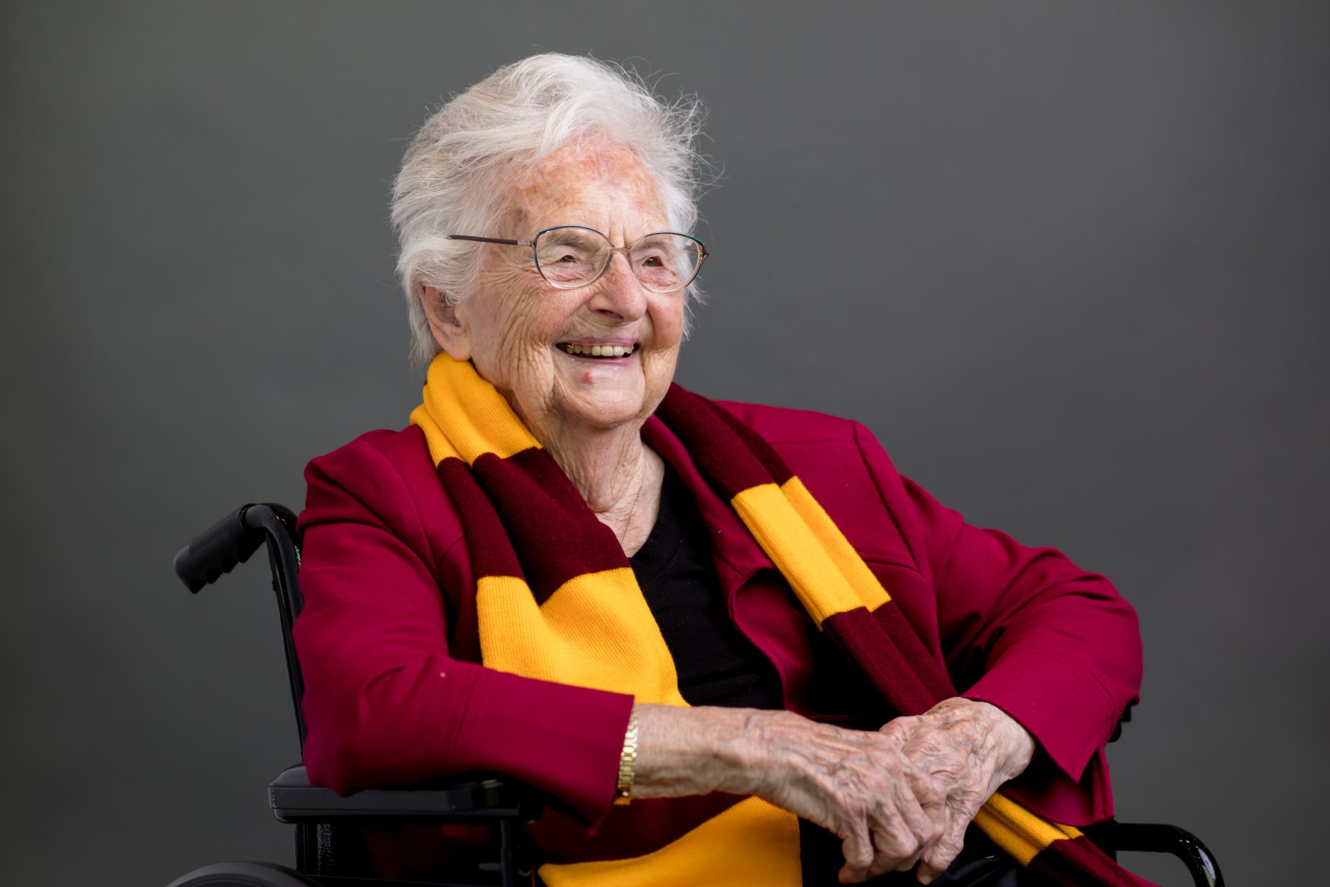 A smiling woman wearing a Loyola University Chicago scarf poses in a wheelchair