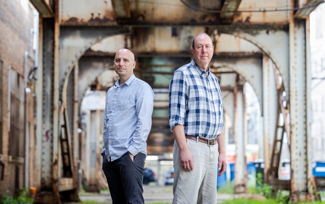 Two Loyola University Chicago professors stand under Chicago's elevated train tracks
