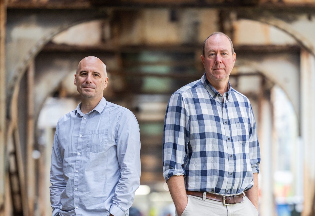 Two men wearing button down shirts stand under the elevated tracks in Chicago