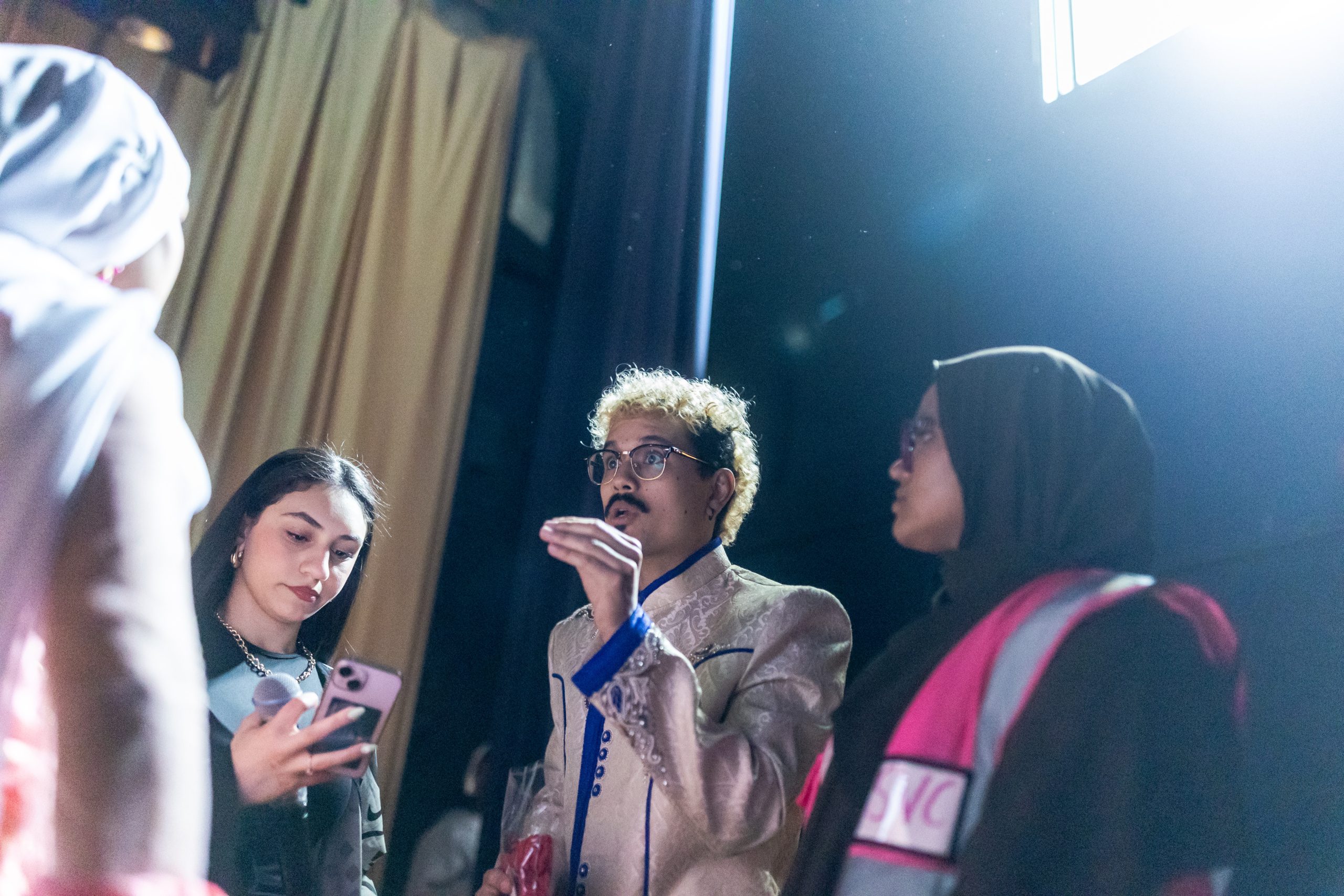 A Loyola University Chicago alum gestures as he speaks to students backstage at Sullivan High School
