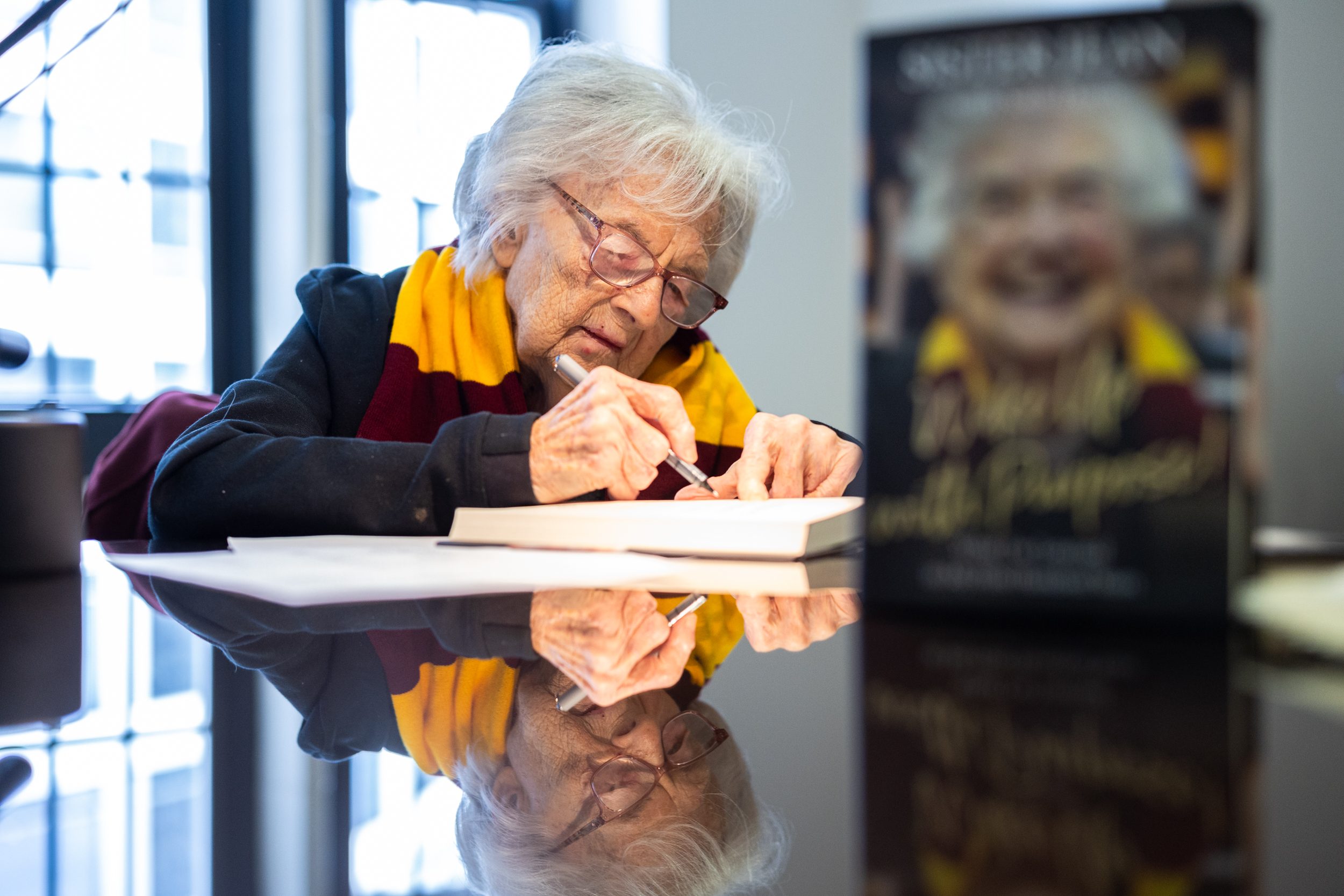 Before the release of her book, Wake Up With Purpose, Sister Jean signs and addresses copies to dignitaries and friends of the University on March 9, 2023. (Photo: Lukas Keapproth)
