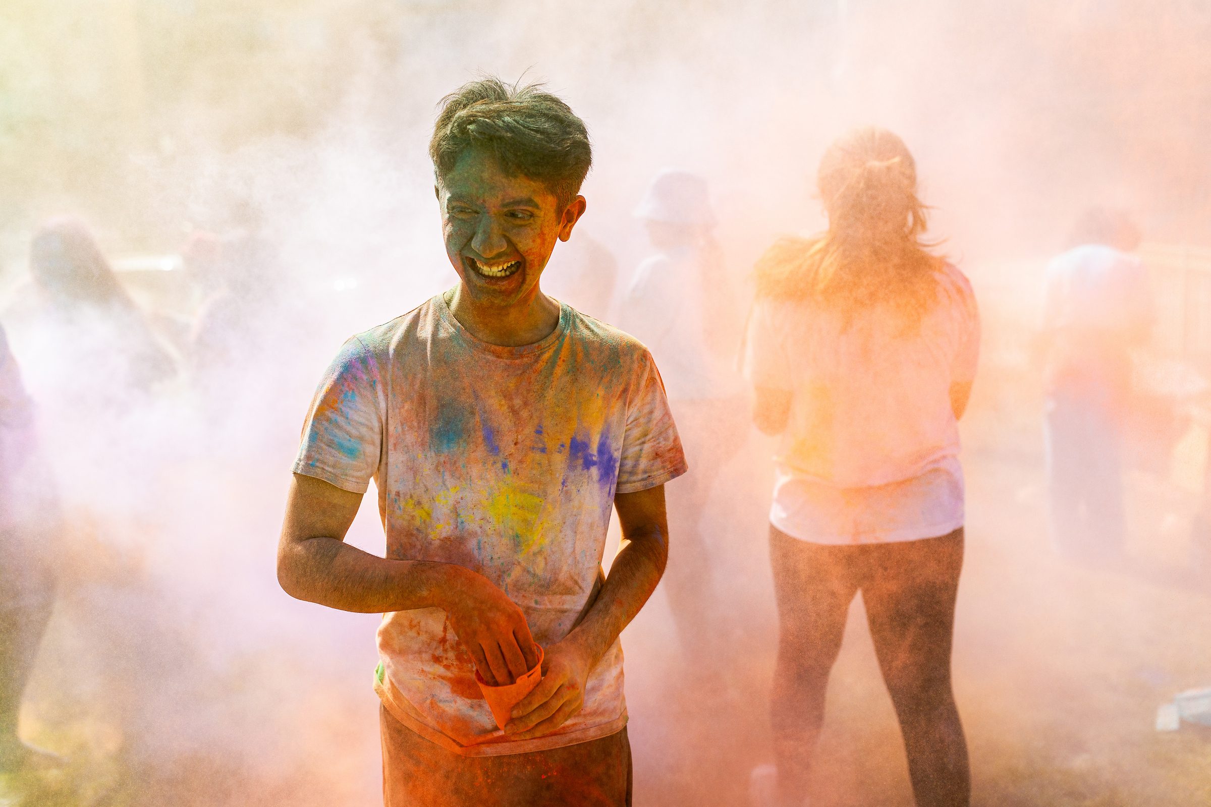 A Loyola University Chicago student laughs as he stands in a cloud of colored powder during Holi, a Hindu celebration of spring.