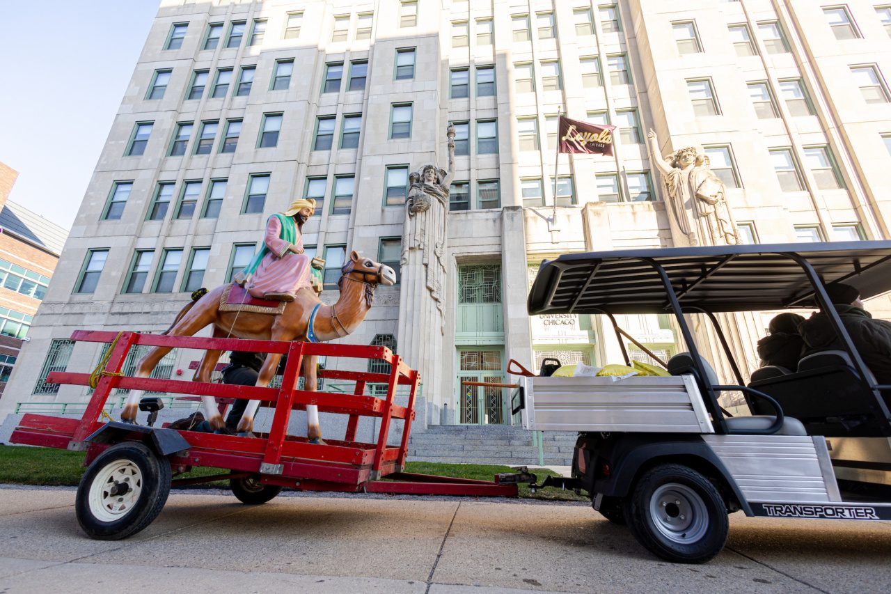 A golf cart tows the figure of a Wise Man atop a camel on Loyola University Chicago's campus