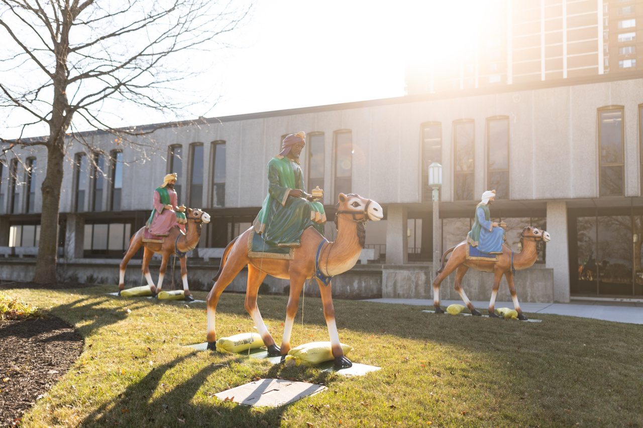 Three fiberglass figures of Wise Men riding camels stand on Loyola University Chicago's campus