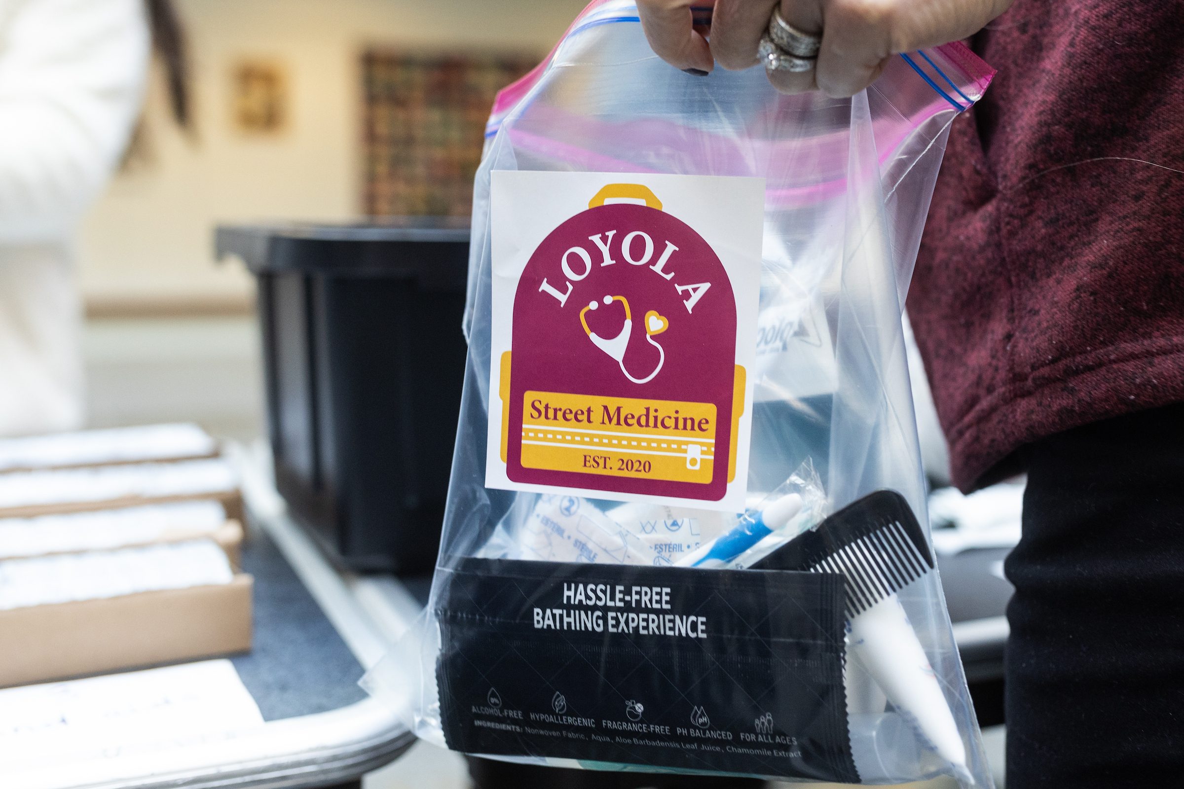 Stritch School of Medicine students and faculty volunteer to assemble hygiene kits for Loyola's Street Medicine Program as part of Martin Luther King Service Days on January 21, 2025. A plastic bag with a Loyola Street Medicine sticker is filled with hygiene and first aid supplies for unhoused people