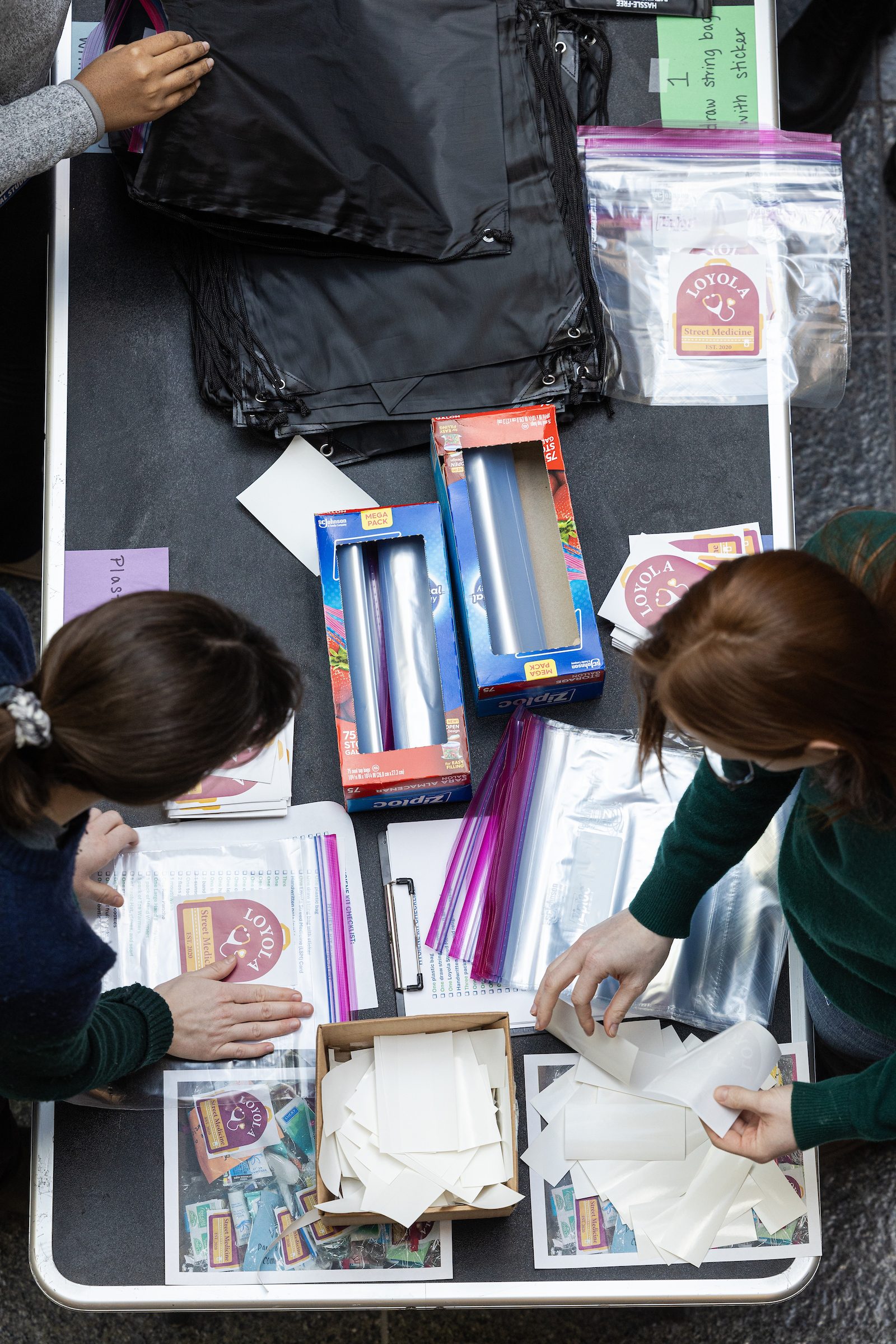 Loyola University Chicago students adhere stickers to plastic bags during an event assembling supplies for homeless individuals