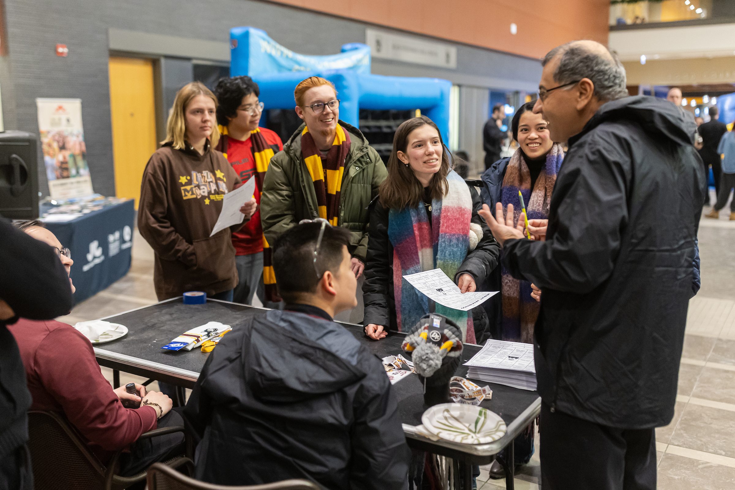 Loyola University Chicago students wearing Loyola sweatshirts and scarves gather around a table at an on-campus event