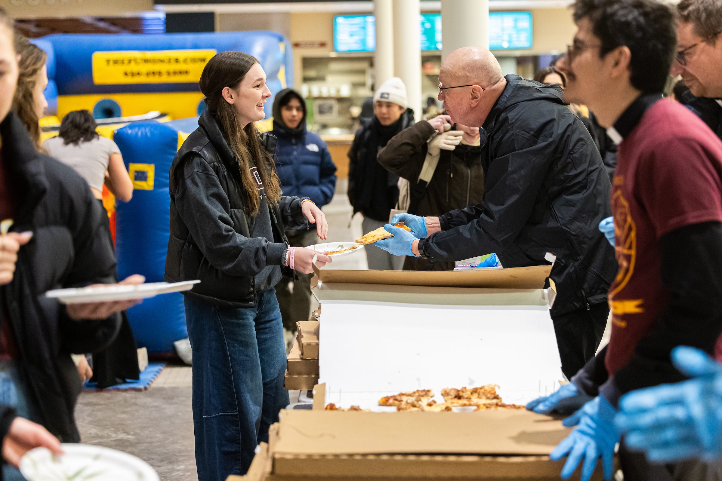 The Jesuit Jam brings students and Jesuits together for a night of pizza and games before a men's basketball game. A Loyola University Chicago student lines up for a slice of pizza at an on-campus event.
