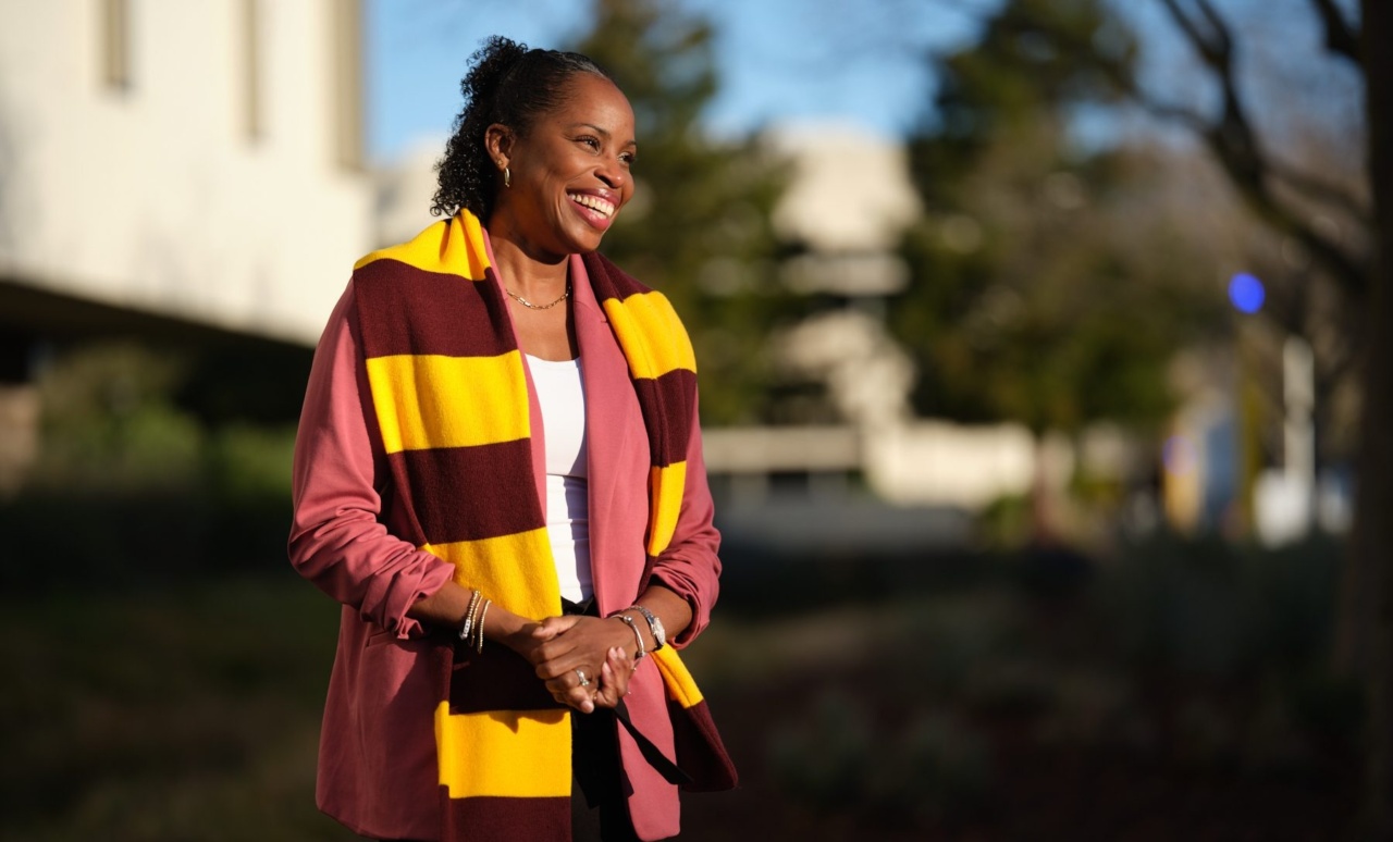 Loyola University Chicago alumna Dr. Marcia Faustin wears a maroon and gold scarf over her pink blazer as she smiles outdoors