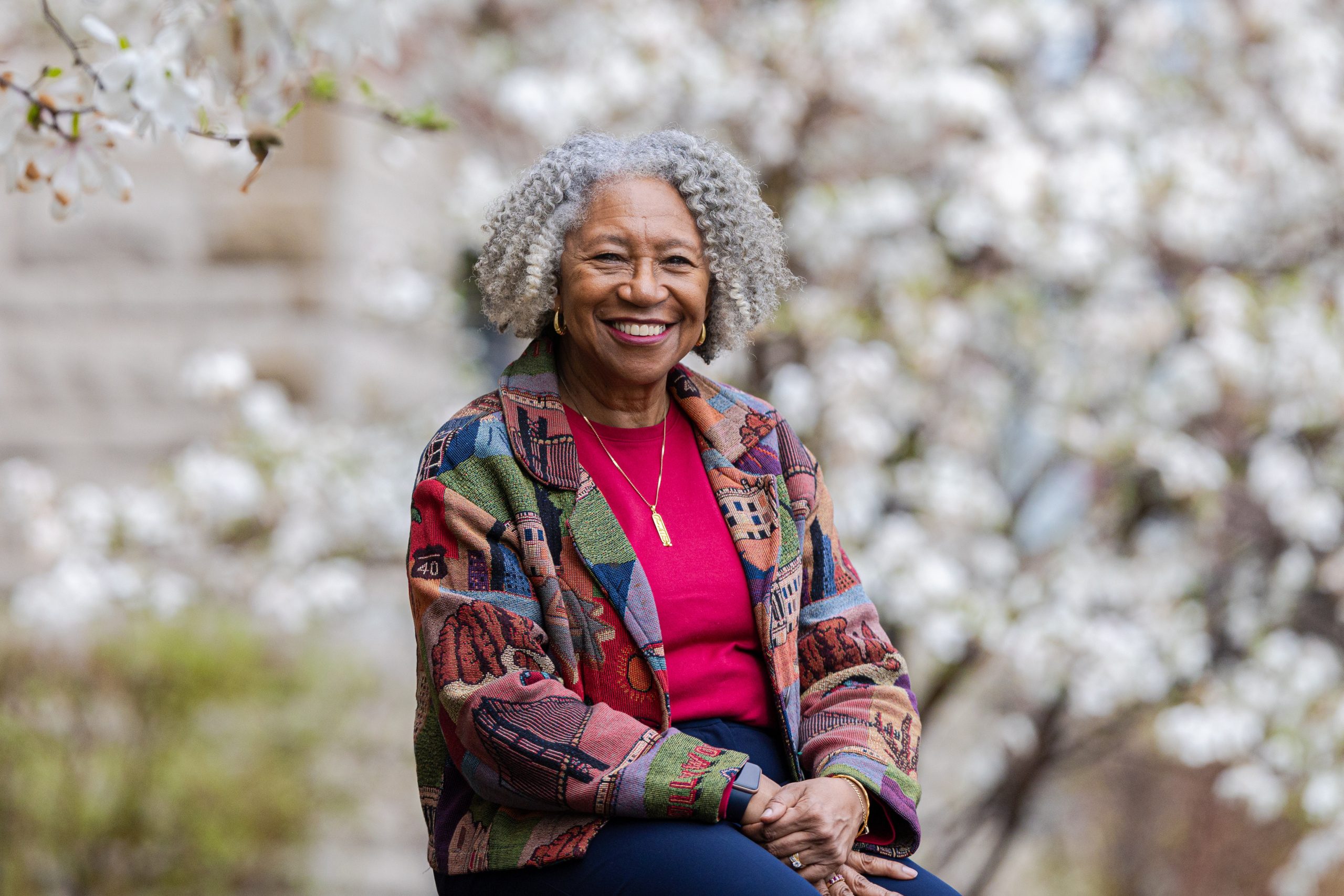 Loyola University Chicago nursing Professor Regina Conway-Phillips smiles in a portrait with blooming trees in the background