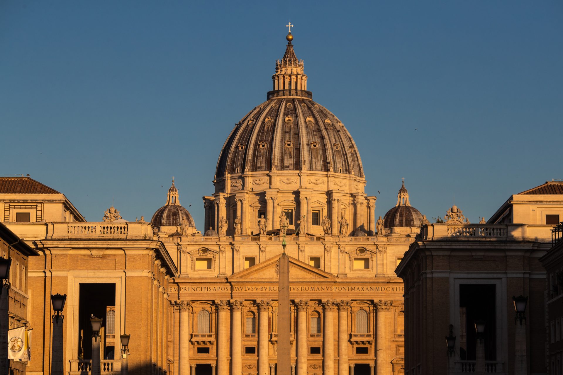 The exterior of St. Peter's Basilica is shown in golden sunlight