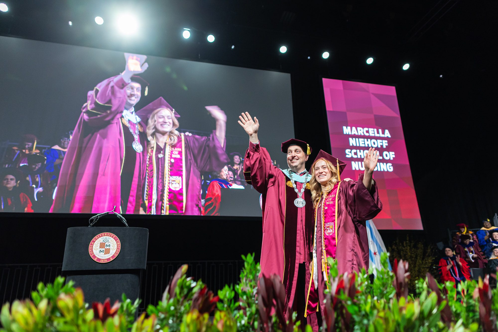 President Mark C. Reed and Aryana Ziakas wave to her family after crossing the stage in the Marcella Niehoff School of Nursing commencement ceremony on May 7.