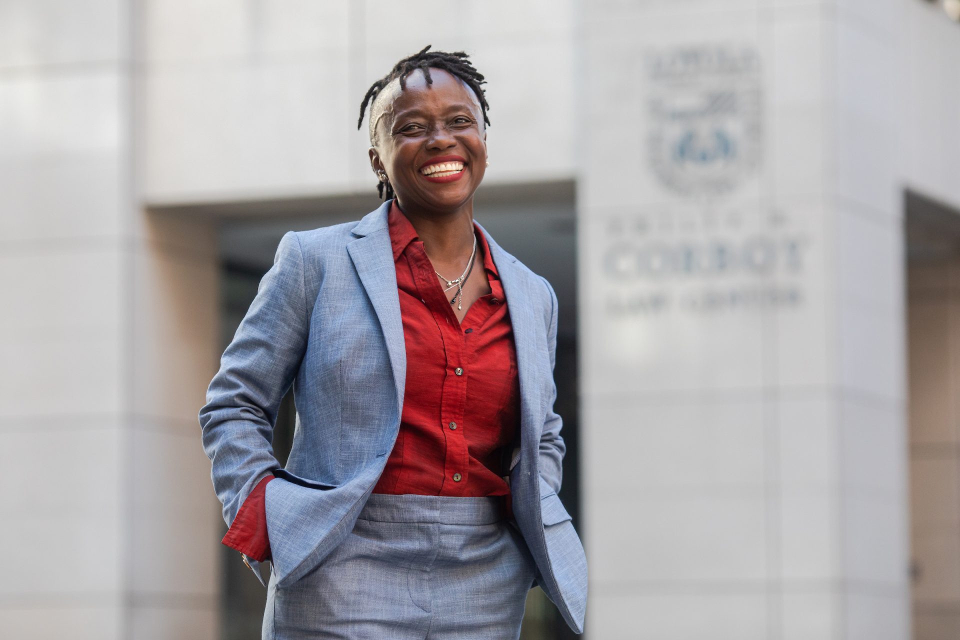 A woman wearing a suit smiles in front of Loyola University Chicago's law school