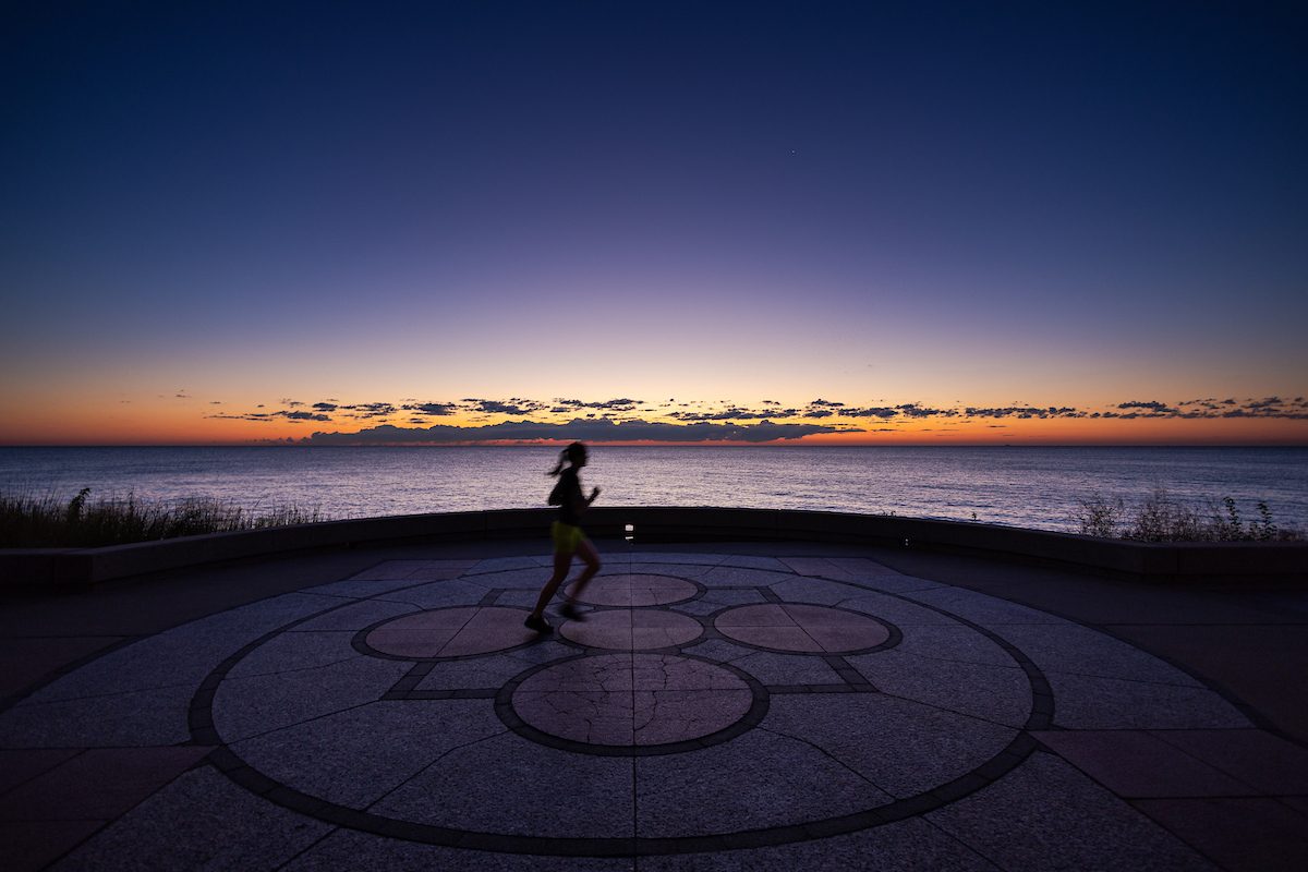 A Loyola University Chicago student jogs along the lakefront at sunrise