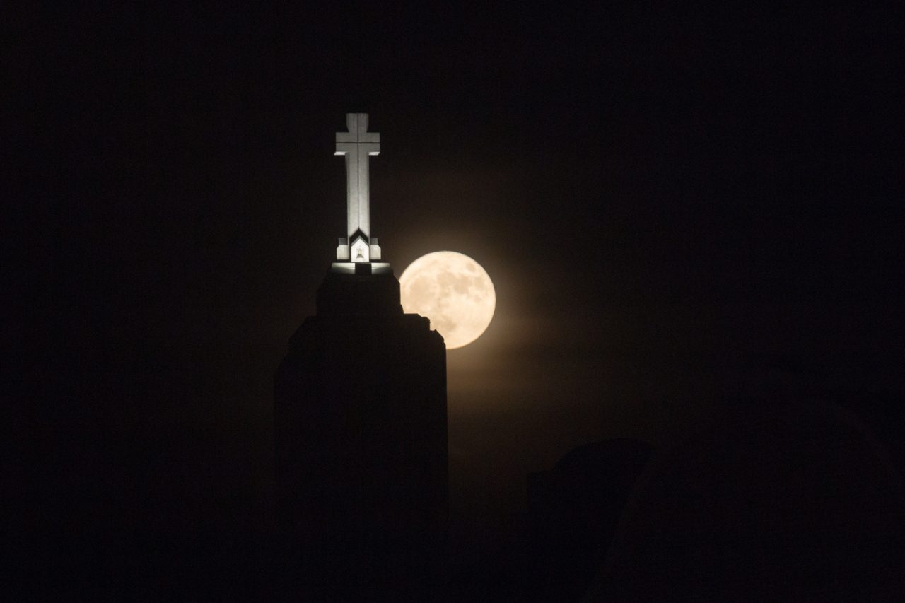 The steeple of Madonna della Strada Chapel with a large moon in the background