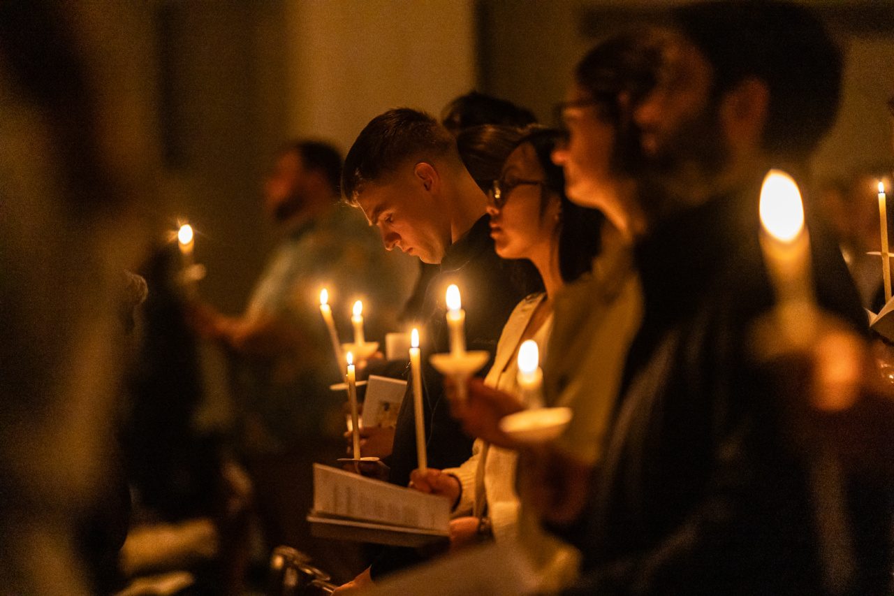 Loyola University Chicago students hold candles and hymn books during a mass on campus