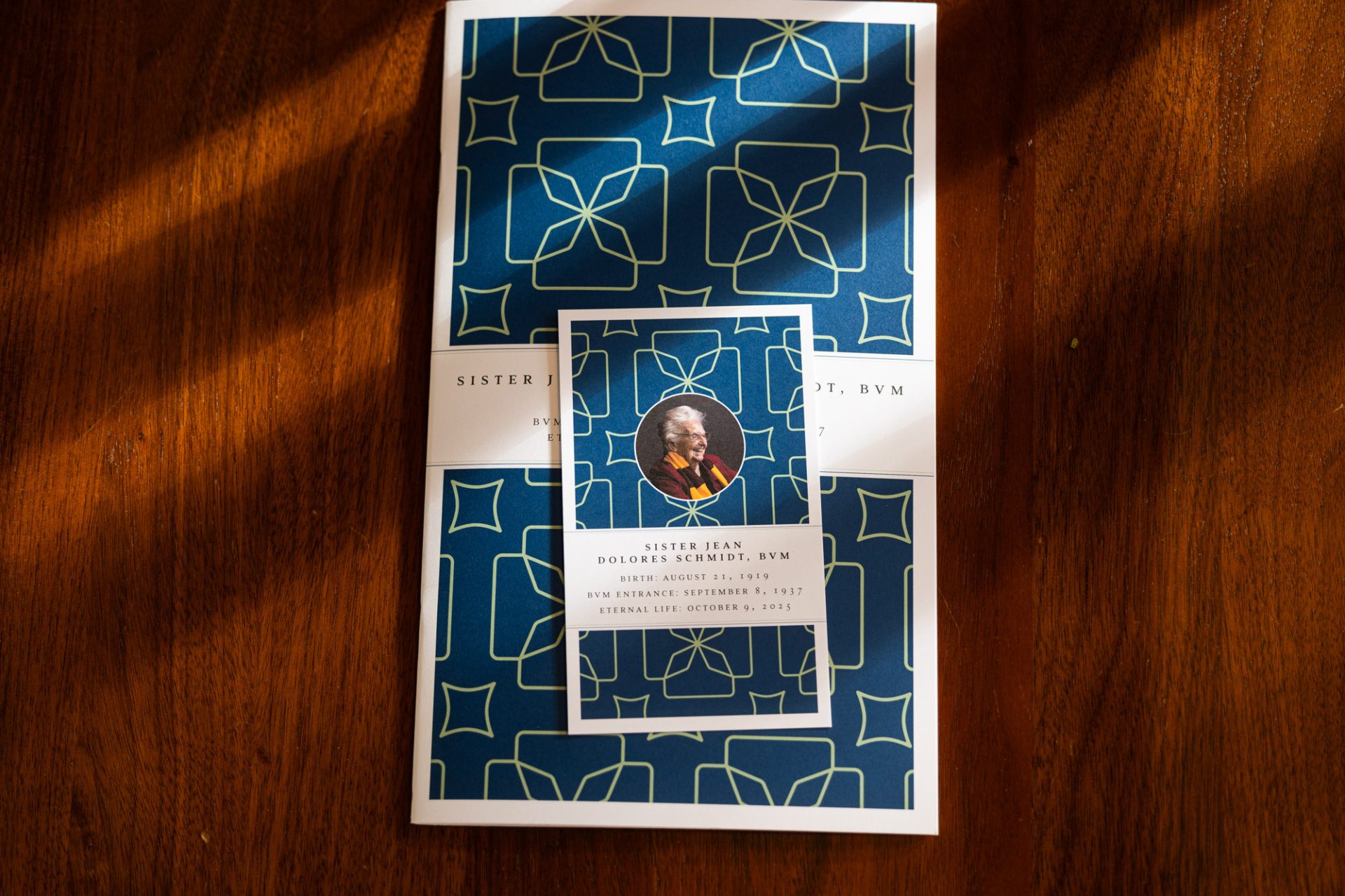 The funeral program for Sister Jean Dolores Schmidt, BVM, lays on a wooden table