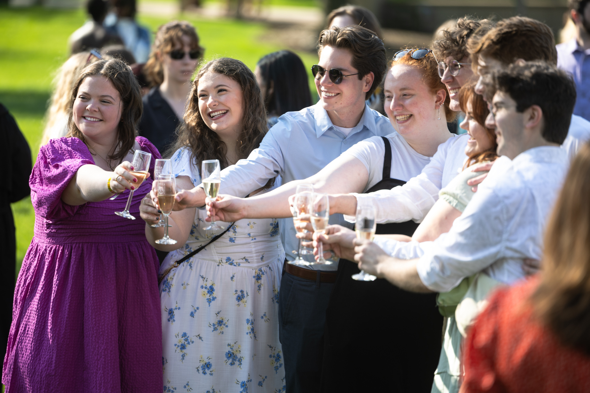 A group of Loyola University Chicago students toast with flutes of sparkling wine outdoors on a sunny day