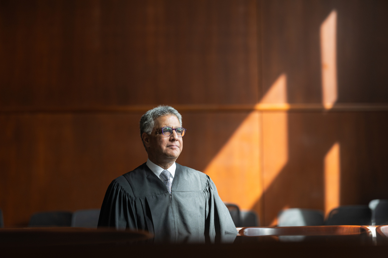 A Loyola University Chicago alumnus wearing robes sits in a wood-paneled courtroom with beams of sunlight streaming in