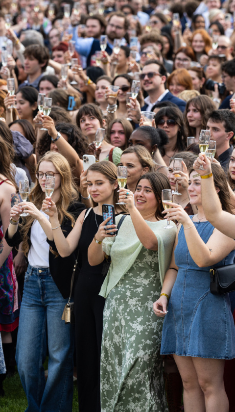A crowd of Loyola University Chicago seniors holds champagne flutes in a toast outdoors