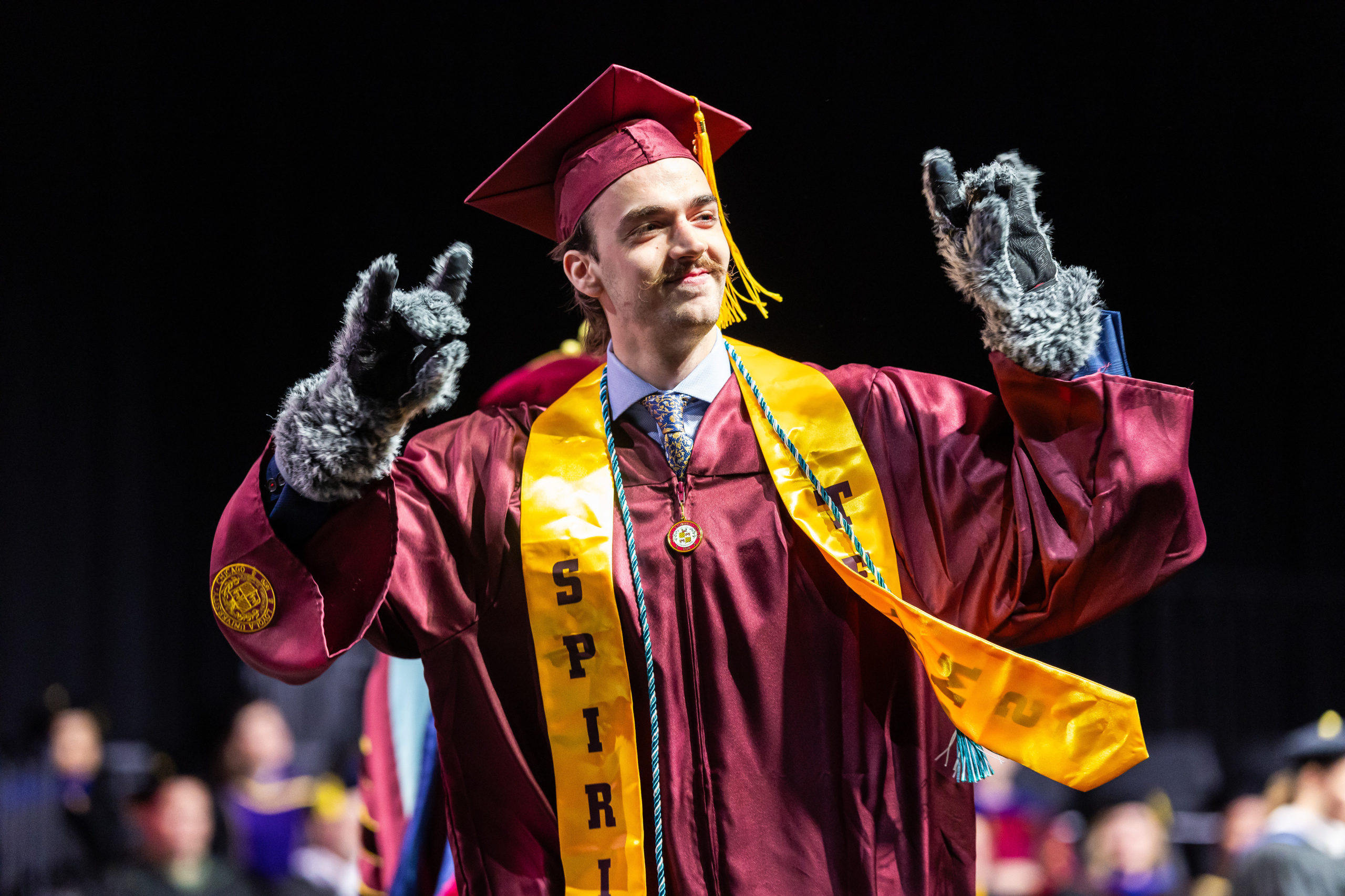 A Loyola University Chicago graduate walks across the stage during a ceremony for the School of Environmental Sustainability and School of Education in Gentile Arena on May 5, 2026. Emily Graslie was the keynote speaker. 
