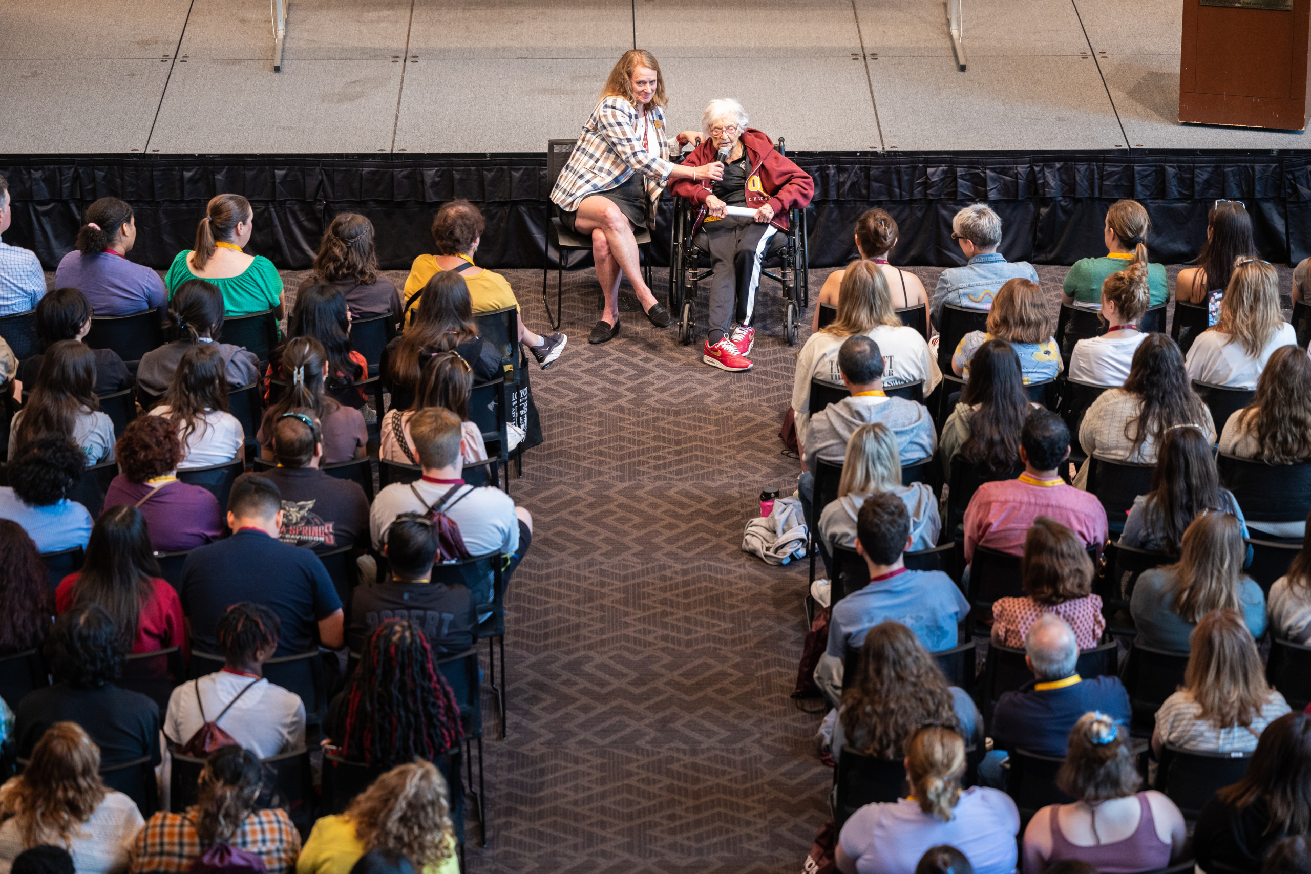 Jane Neufeld, left, holds the microphone for Sister Jean Dolores Schmidt, BVM, right, as she welcomes incoming students and their families to campus during New Student Orientation on June 15, 2023.