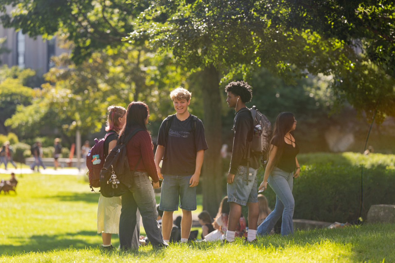 A group of Loyola University Chicago students talk outdoors on campus on a sunny day