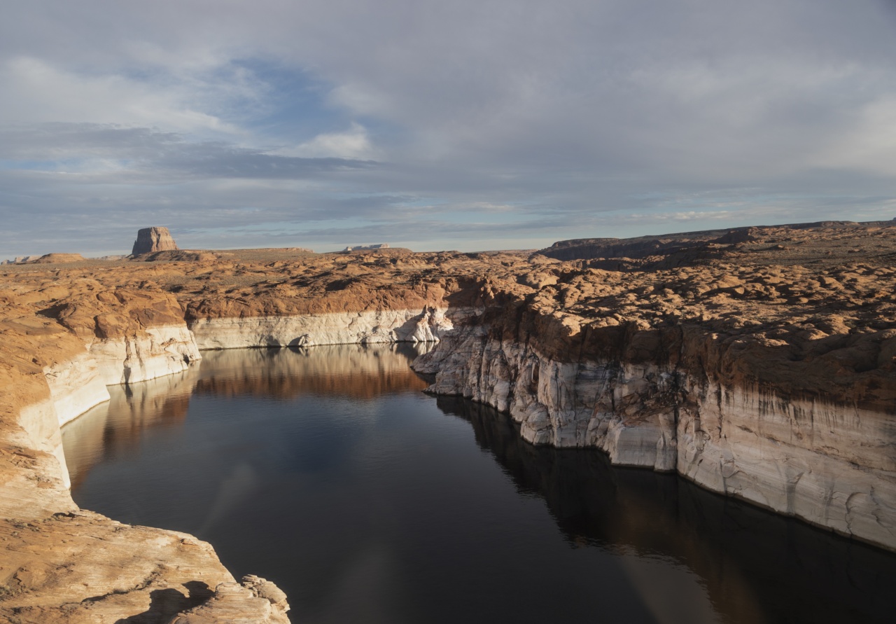 A lake with a water level sitting feet below the shoreline is shown in a desert in golden light with a cloudy sky