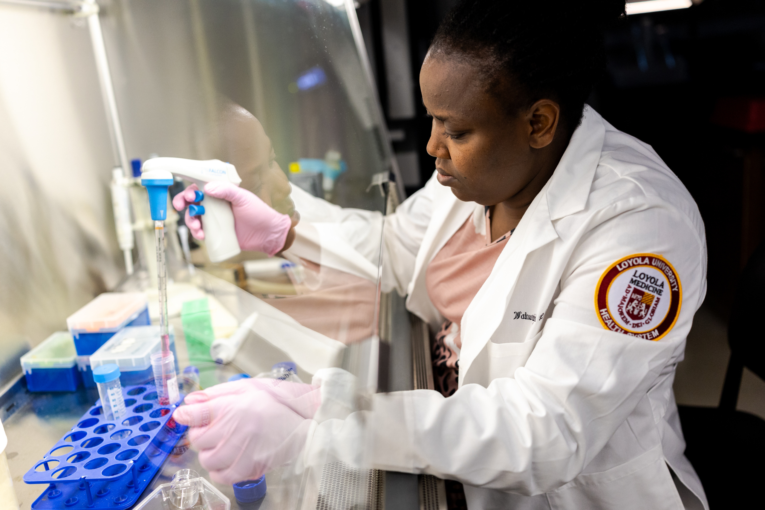 Research Associate Oluwatomilayo Patience Odum measures liquid into a test tube in Derek Wainwright's lab on the Health Sciences Campus. 